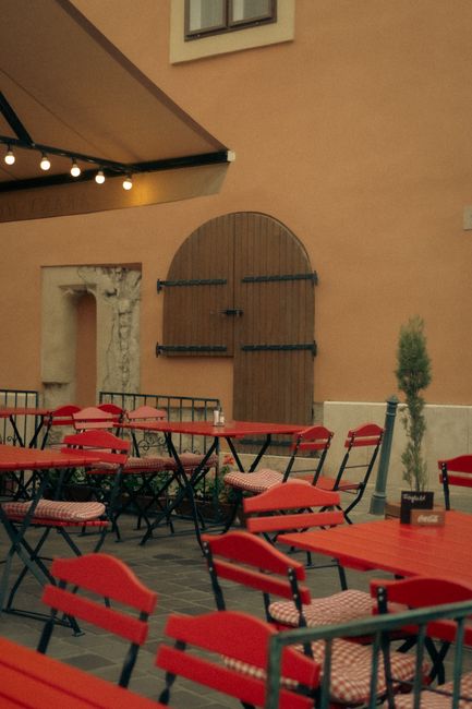 Captivating view of a cozy outdoor café setting featuring vibrant red tables and chairs.