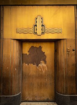 A weathered Art Deco doorway with geometric design in an urban environment.. weathered, deco, doorway