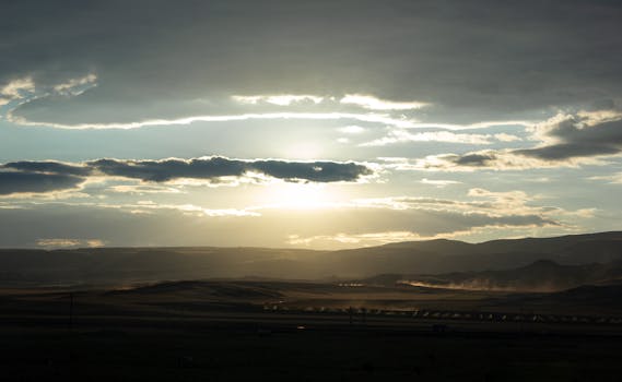 Stunning sunrise scenery over hills with dramatic clouds and light rays.