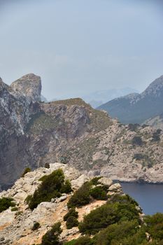 Panoramic cliffside view of the Balearic Sea with rocky landscapes and lush greenery.