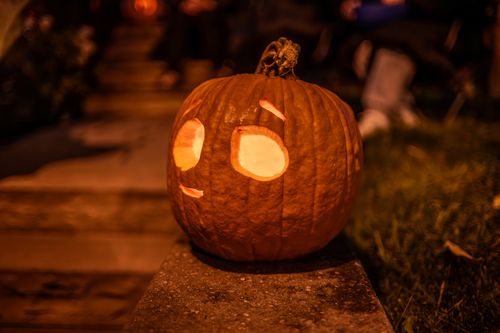 Free Whimsical carved pumpkin on a doorstep during Halloween night, glowing brightly outdoors. Stock Photo