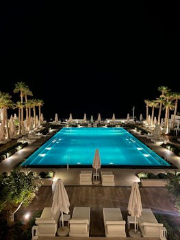 Elegant night view of luxury poolside at a Crete resort with palm trees and gentle lighting.