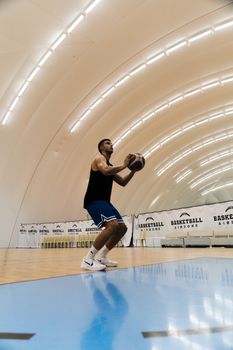 A basketball player focuses on a free throw in a modern indoor court in Greece.