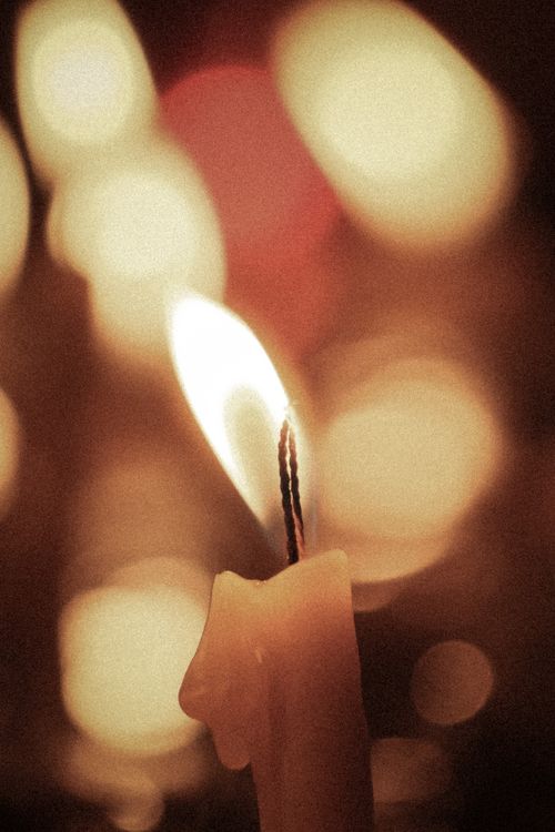 Free Close-up of a candle flame with a warm, bokeh background, creating a cozy ambiance. Stock Photo