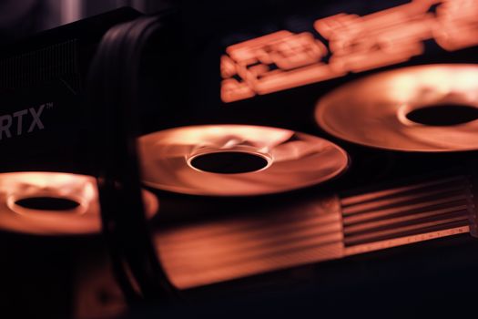 Dynamic close-up shot of illuminated gaming graphics card fans in red light, showcasing cutting-edge technology.