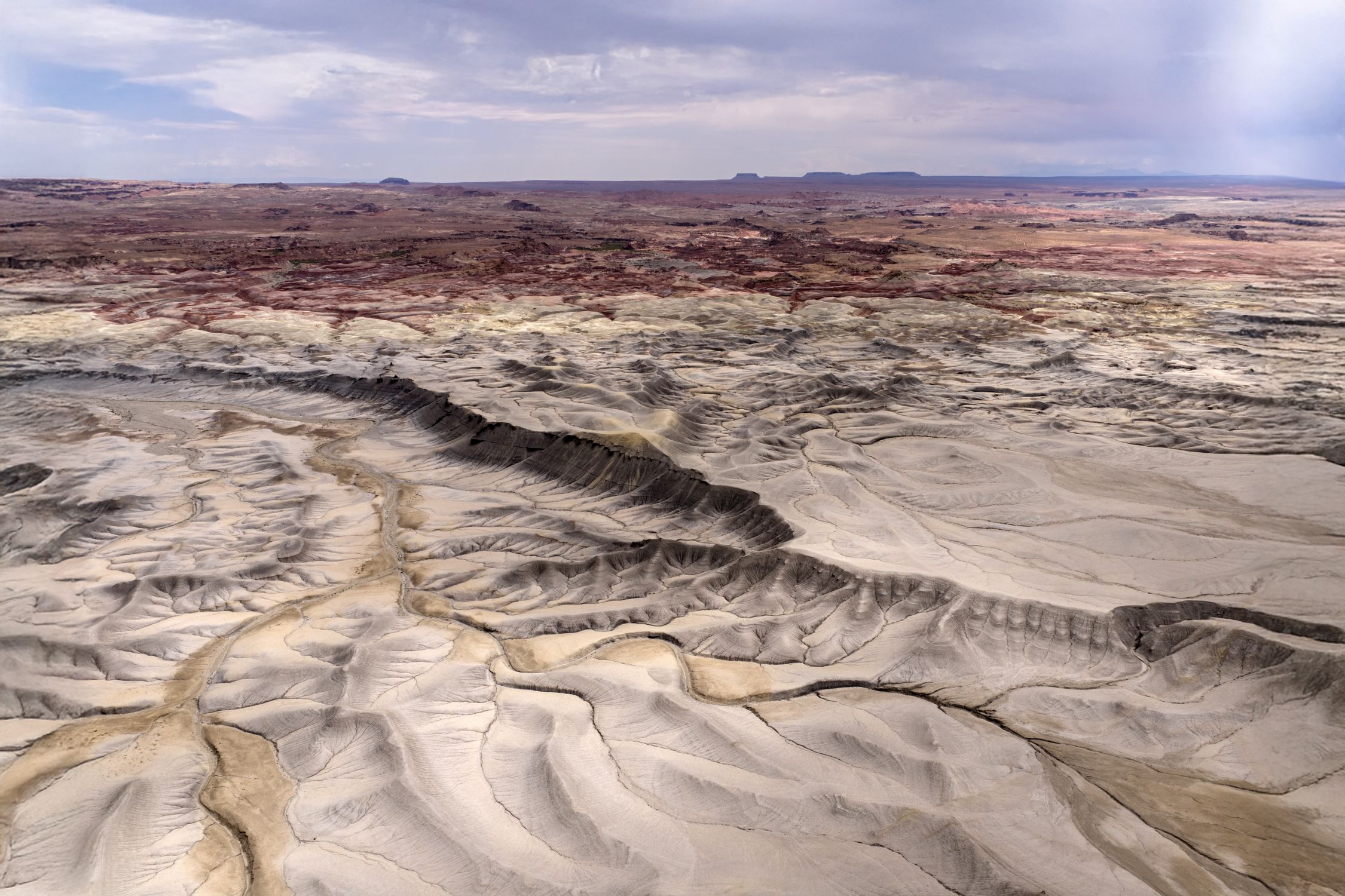 Aerial view showcasing Utah's rugged and colorful desert terrain under a cloudy sky.