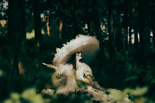 A woman with skeletal makeup wearing a large feathered hat in a mystical forest setting.