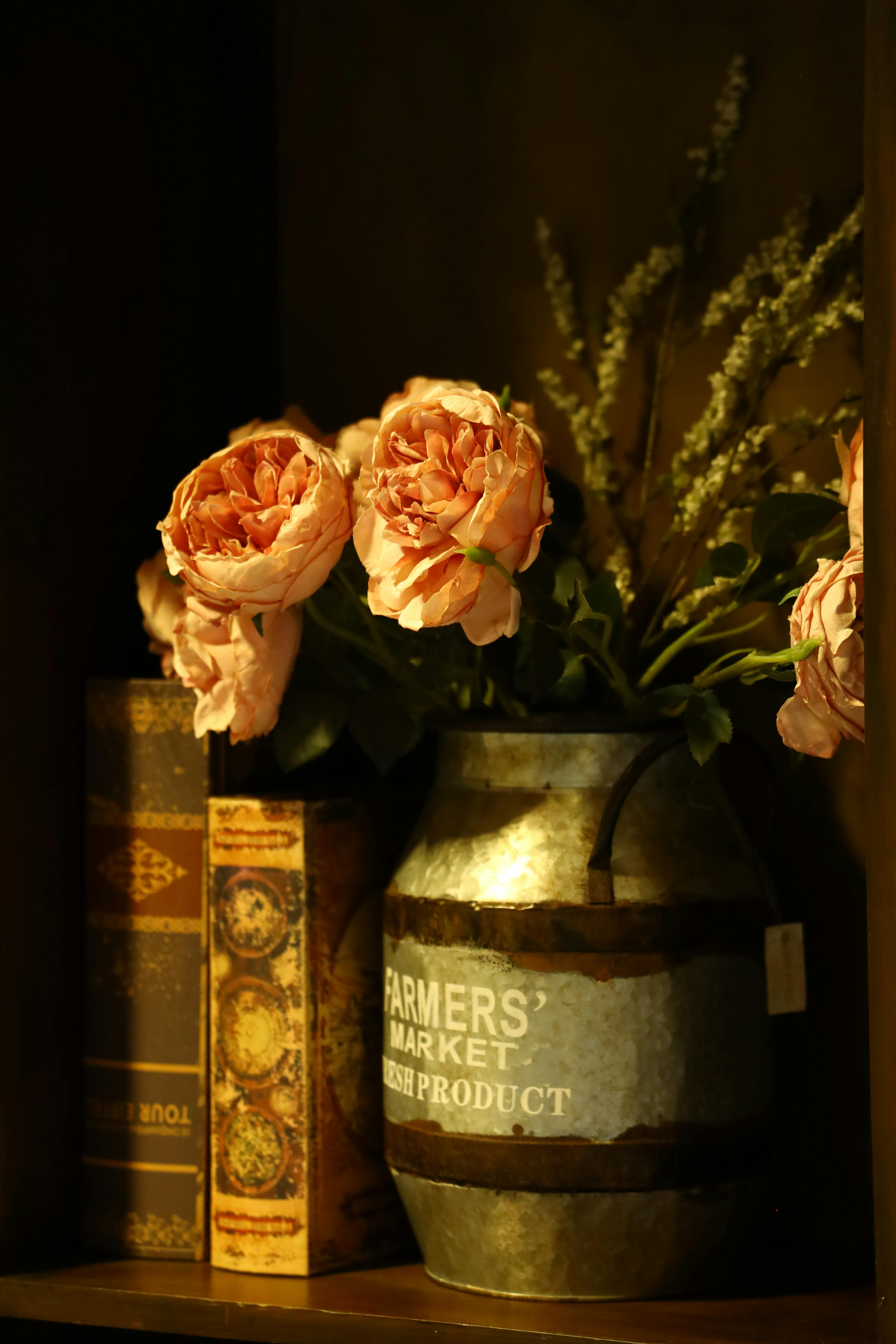 Gratuit Trandafiri într-o vază metalică vintage alături de cărți antice, creând o atmosferă confortabilă și nostalgică. Fotografie de stoc