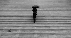 一名妇女撑着伞爬楼梯的灰色剪影