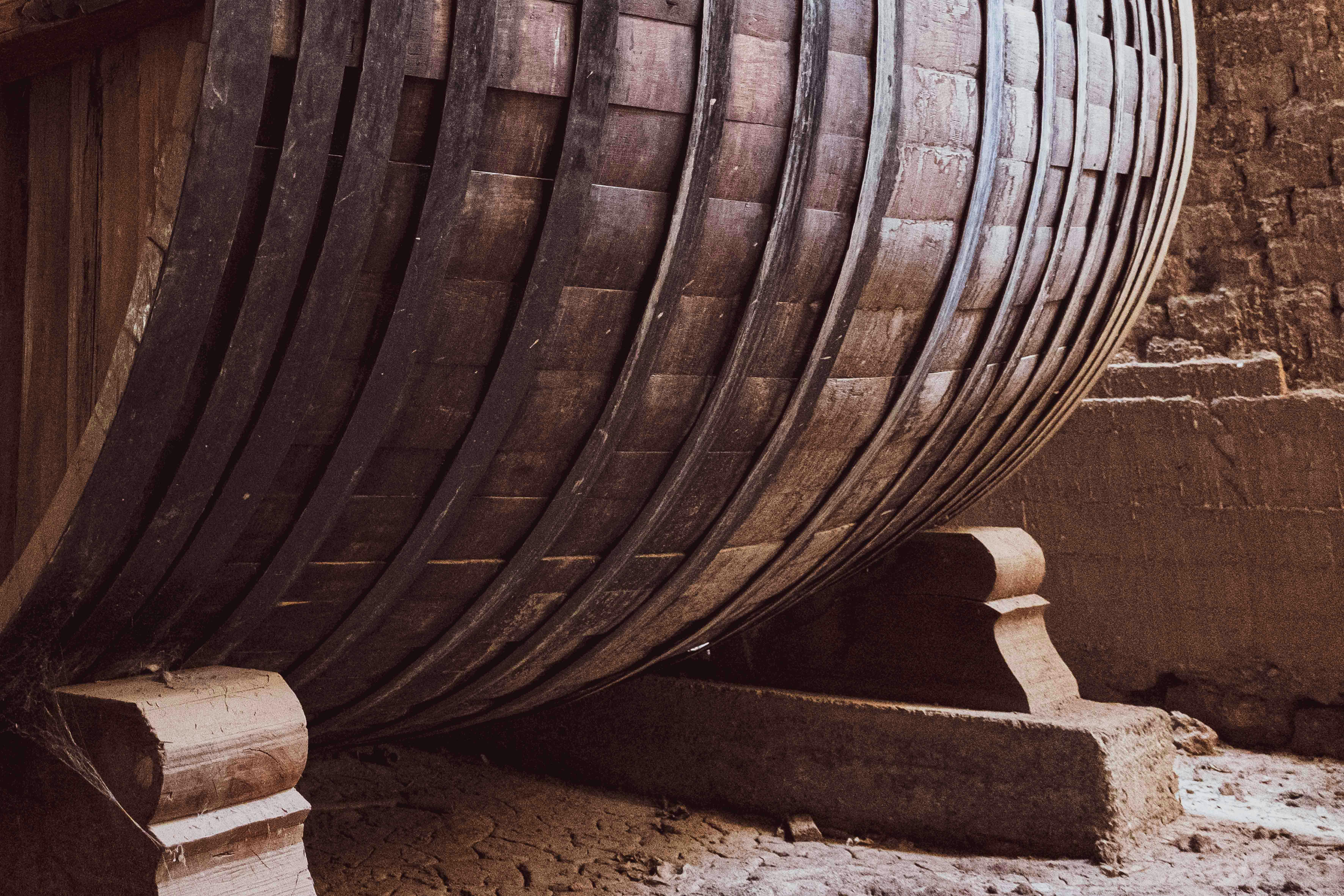 Close-up of a large wooden wine barrel in an ancient wine cellar, highlighting the historic architecture.