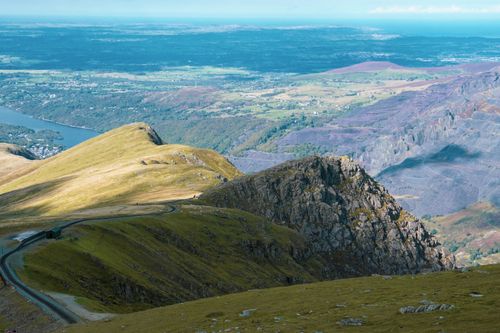 Free Breathtaking aerial view of Snowdonia's rolling hills and winding roads in natural sunlight. Stock Photo