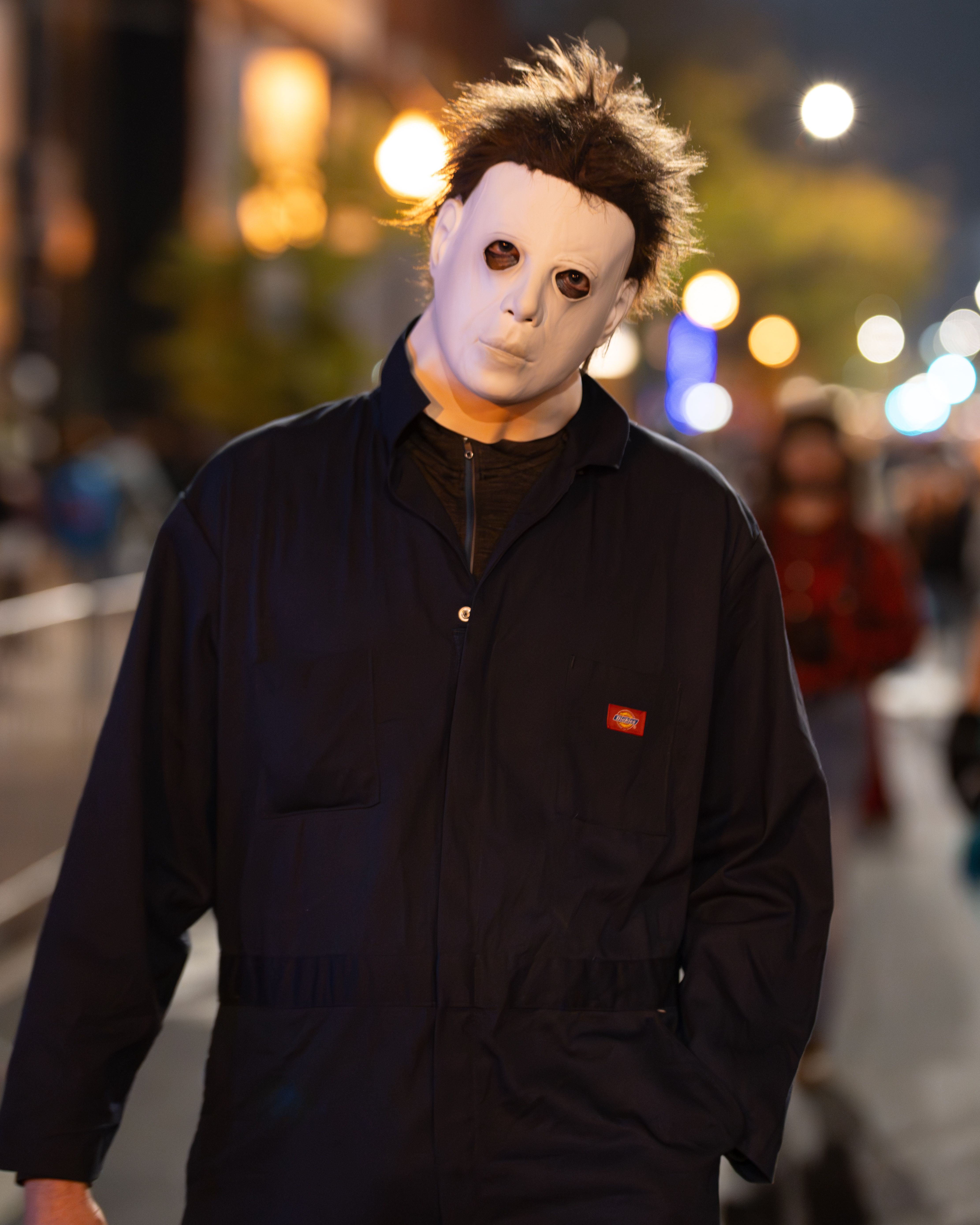 A masked figure participates in the Halloween parade in Chicago. Night street photography.
