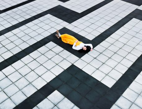 一位女士身着充满活力的服装，在引人注目的几何瓷砖地板上放松身心，将艺术与现代设计融为一体