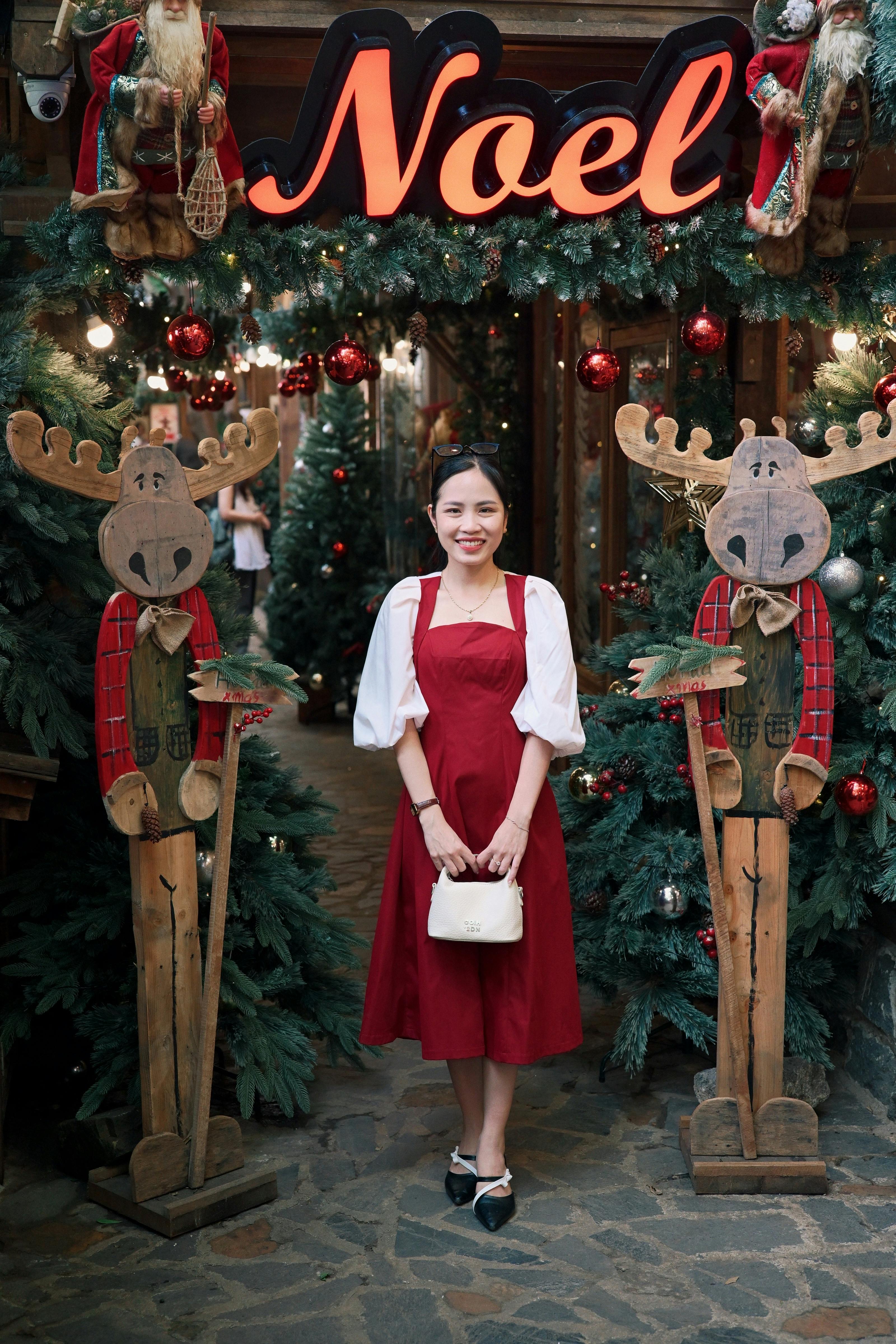 Woman in red dress standing at a decorated entrance with Christmas theme.