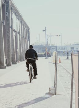 Cyclist rides along an industrial street with factories in the background.