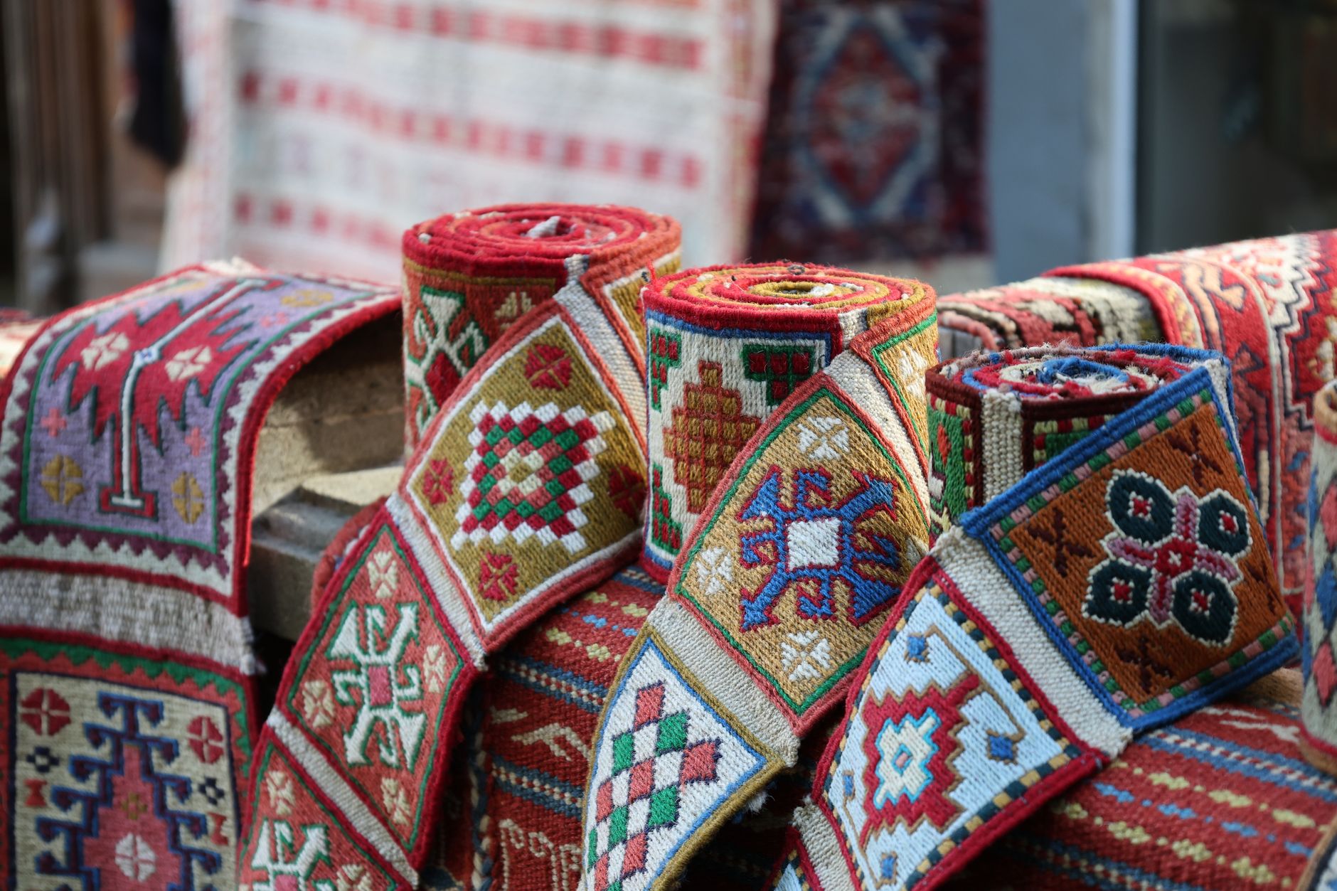 Vibrant rolled textiles featuring geometric patterns in a market setting, showcasing cultural craftsmanship.