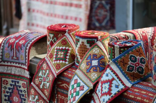 Free Vibrant rolled textiles featuring geometric patterns in a market setting, showcasing cultural craftsmanship. Stock Photo