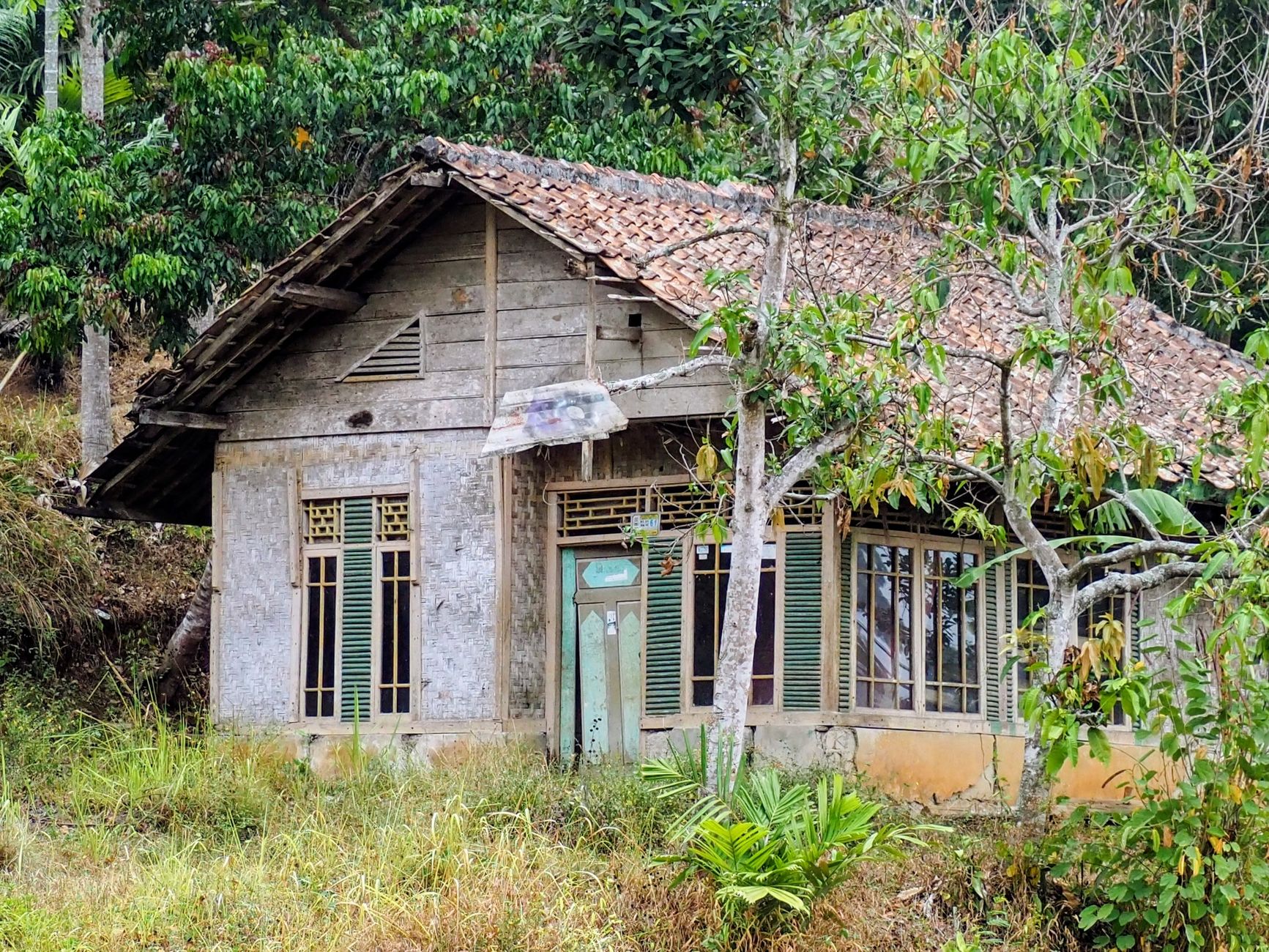 An old wooden house surrounded by greenery in West Java, Indonesia.