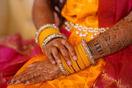 Close-up of colorful bridal bangles and intricate henna designs on hands.