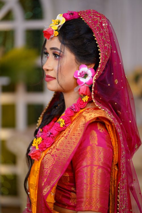 Free Side profile of a South Asian bride in vibrant traditional attire adorned with floral jewelry. Stock Photo