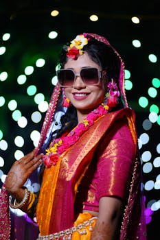 Smiling bride in traditional attire with flowers and lights, creating a festive atmosphere.