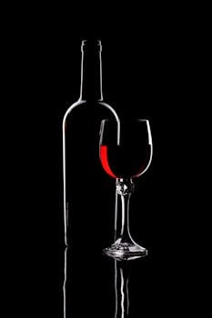 Artistic silhouette of a wine bottle and glass with red wine, perfect for elegant themes.