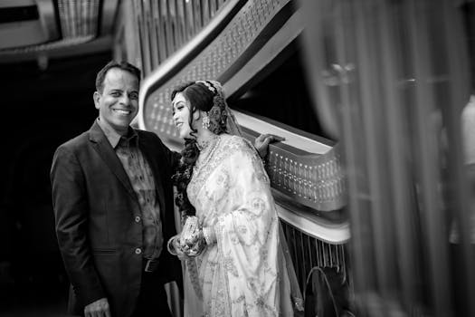A beautiful black and white portrait of a couple in traditional wedding attire, sharing a joyful moment indoors.