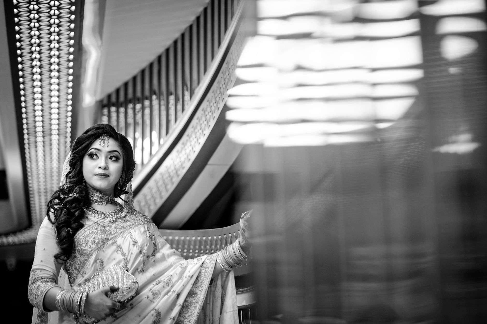 Stunning black and white portrait of a South Asian bride in traditional attire captured indoors with artistic composition.