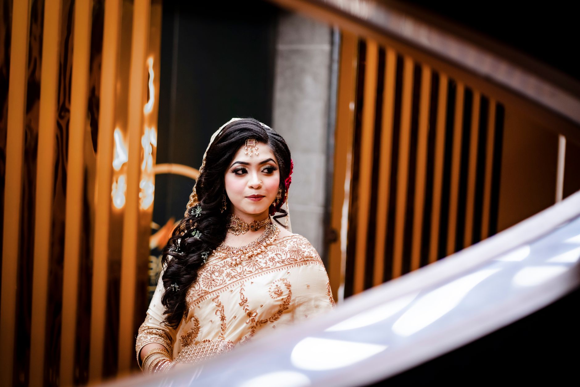 A stunning South Asian bride dressed in intricate traditional attire with beautiful henna designs, captured indoors with artistic framing.