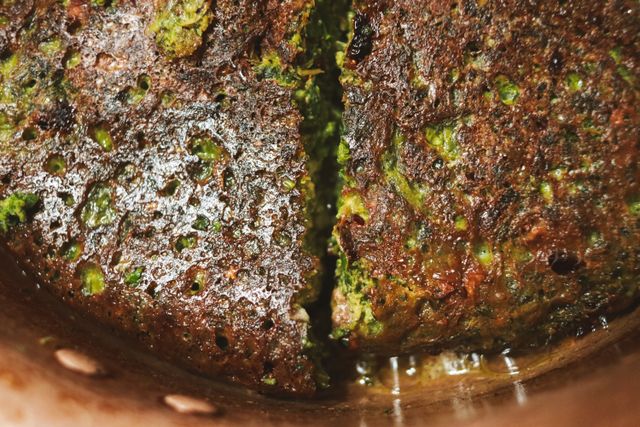 Deliciously crispy green vegetable fritter close-up with a textured surface, perfect for food enthusiasts.