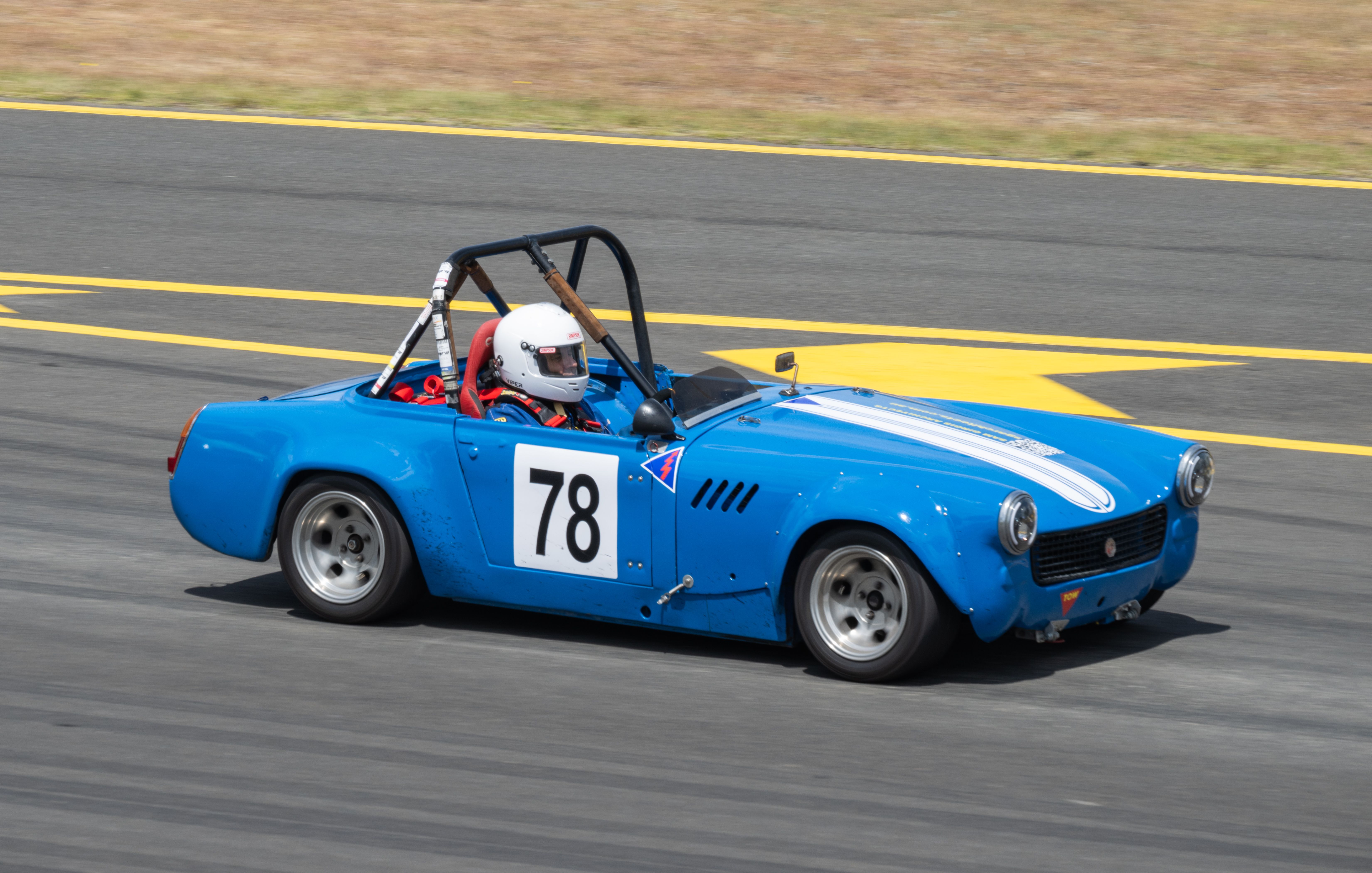 grátis Carro de corrida clássico azul, número 78, em alta velocidade na pista em um dia ensolarado. Foto profissional