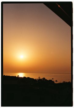 A beautiful sunset casting warm hues over a calm ocean and coastline.