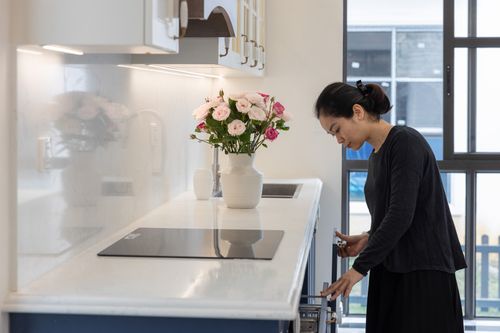 Free Woman in a modern kitchen beside roses, showcasing contemporary design. Stock Photo