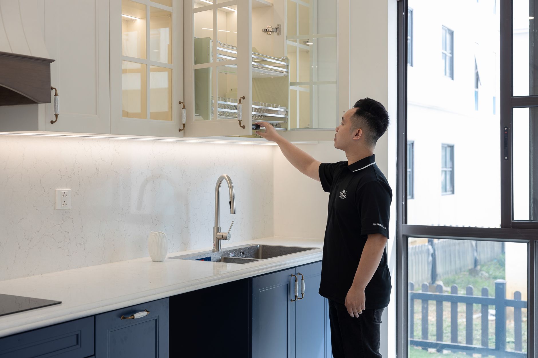 high end apartment storage with smart home gadgets A person organizing a modern kitchen cabinet with elegant design and bright lighting.