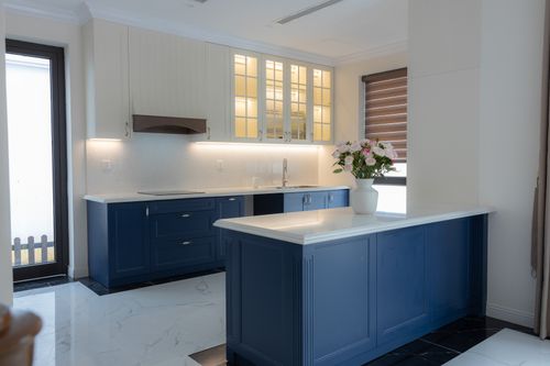 Free Elegant kitchen with blue cabinets, white countertops, and a vase of flowers. Stock Photo