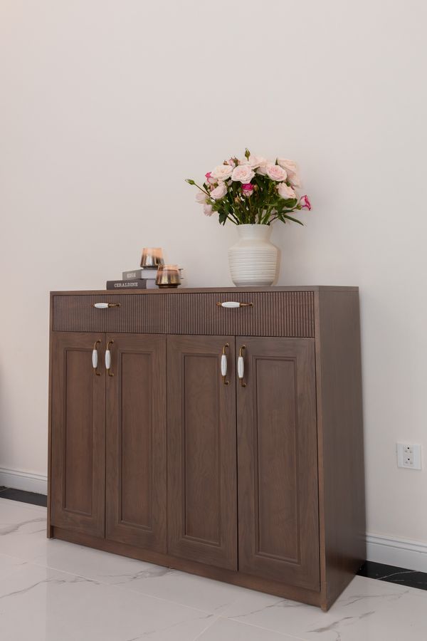 Wooden storage cabinet in a minimalist room with fresh flowers — photo by HONG SON on Pexels