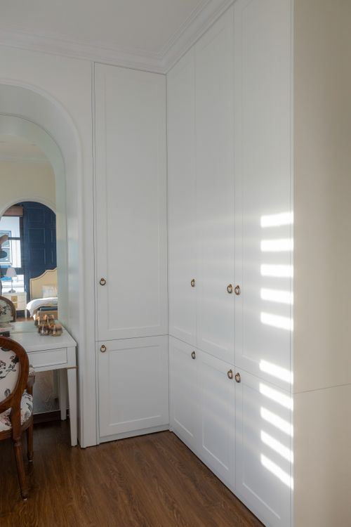 Free Sunlit corner of a modern room showcasing sleek white cabinetry and wooden flooring. Stock Photo