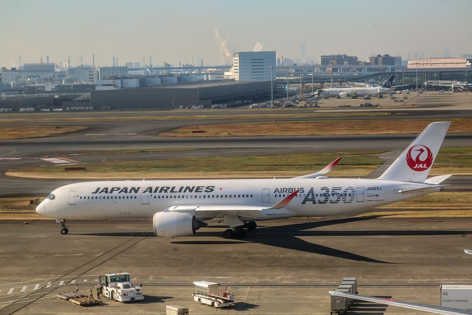 Japan Airlines Airbus A350 on runway at airport, clear day.