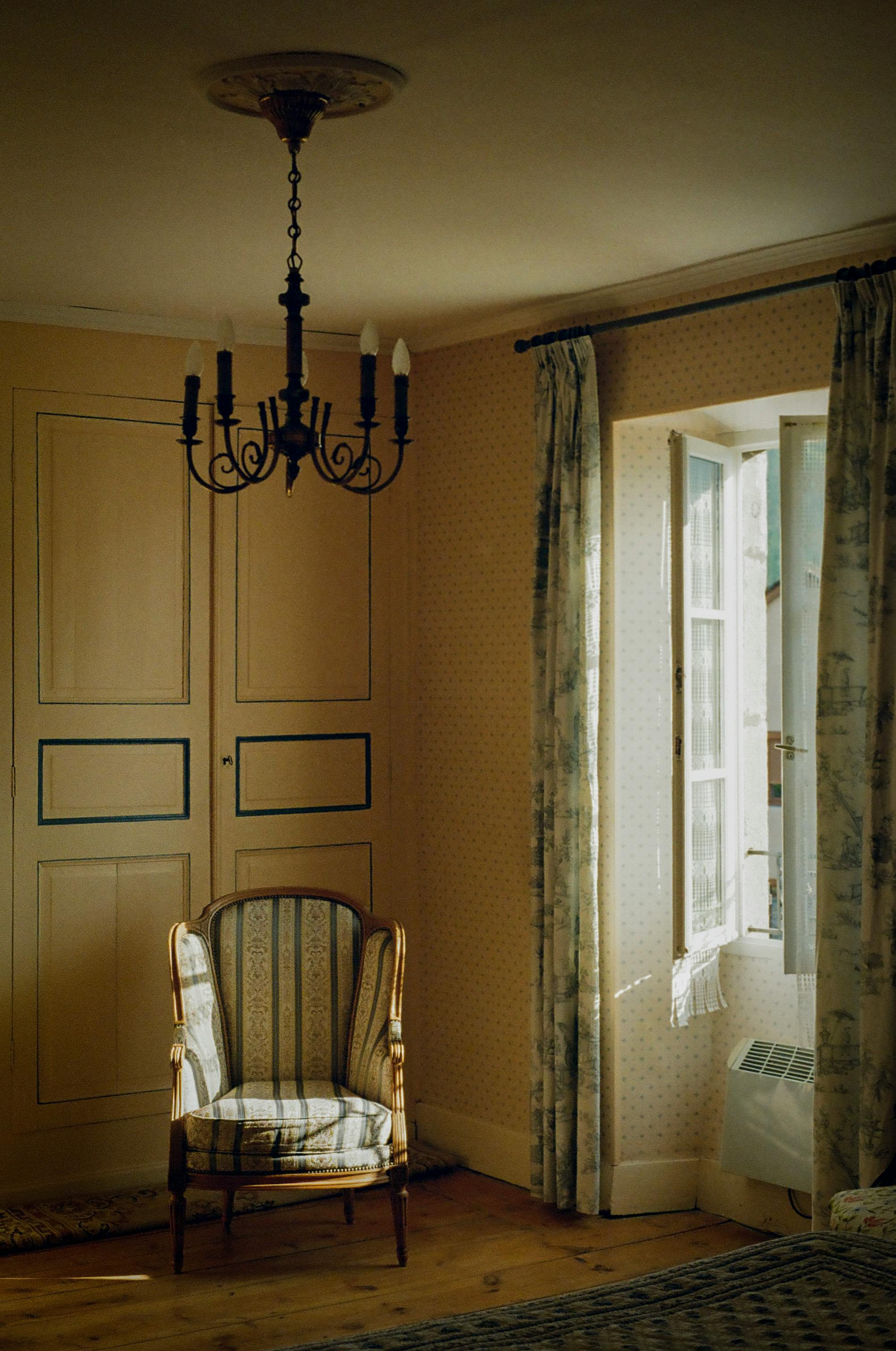 Sunlit vintage interior room with antique chair and open window, exuding warmth.