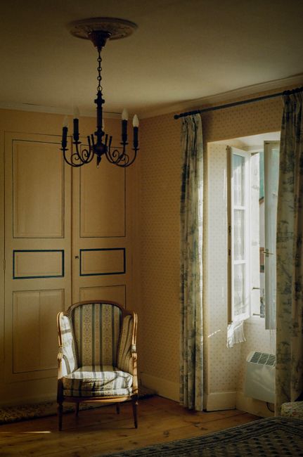 Sunlit vintage interior room with antique chair and open window, exuding warmth.