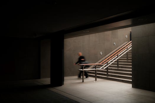 Dark underground passage with motion blur of person near stairway. Modern architectural design.