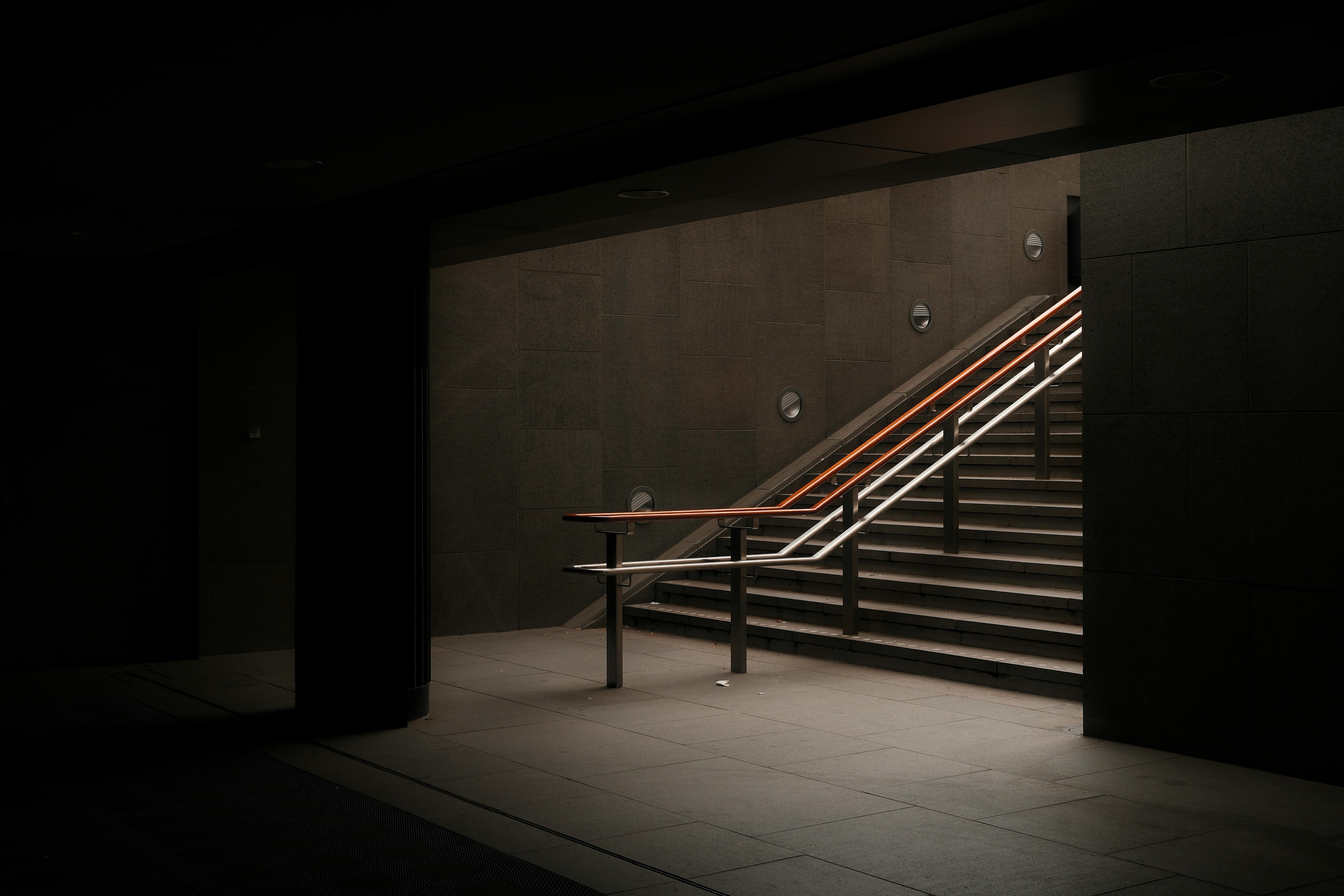 A dimly lit underground staircase offering a minimalist and moody atmosphere.