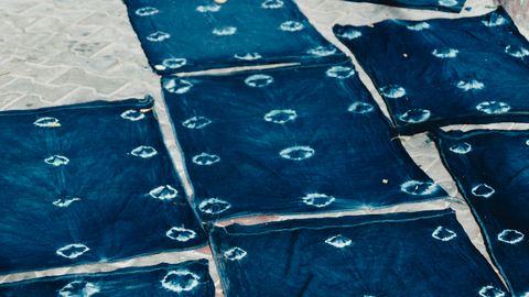 Indigo-dyed textiles drying outdoors, showcasing traditional dye methods.