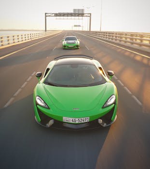 Two vibrant green supercars speeding on a highway during sunrise, showcasing luxury and performance.