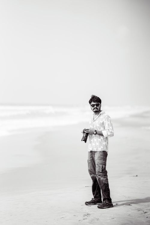 Free Captivating black and white photo of a man holding a camera on a serene beach Stock Photo