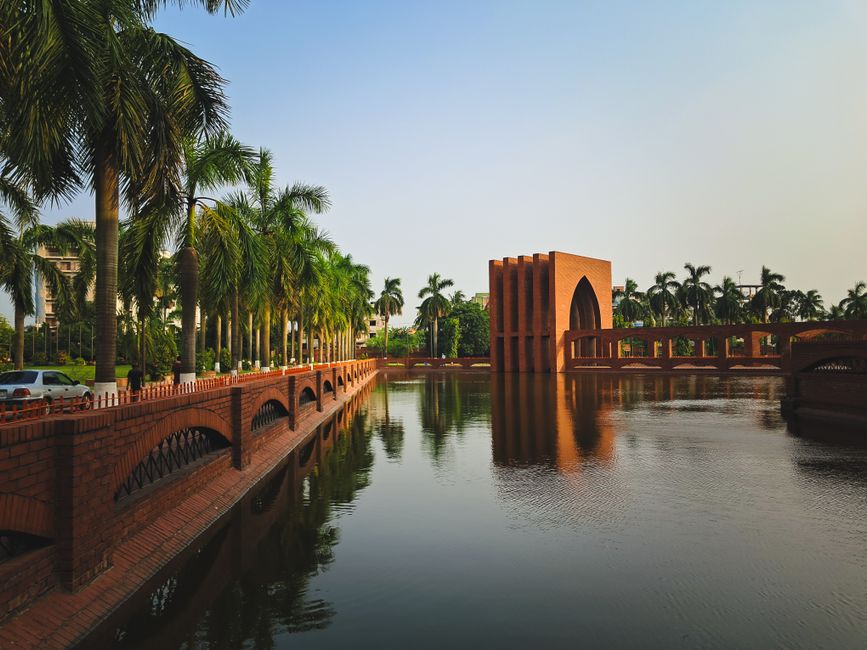 Peaceful scene of palm trees and architecture reflected in calm water.