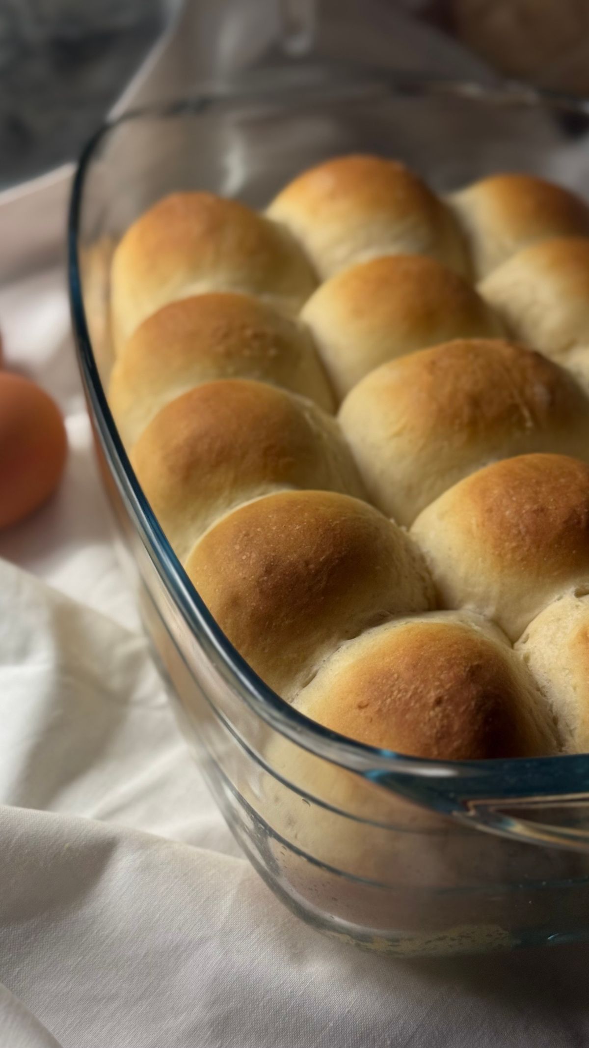 Golden baked dinner rolls in a glass dish