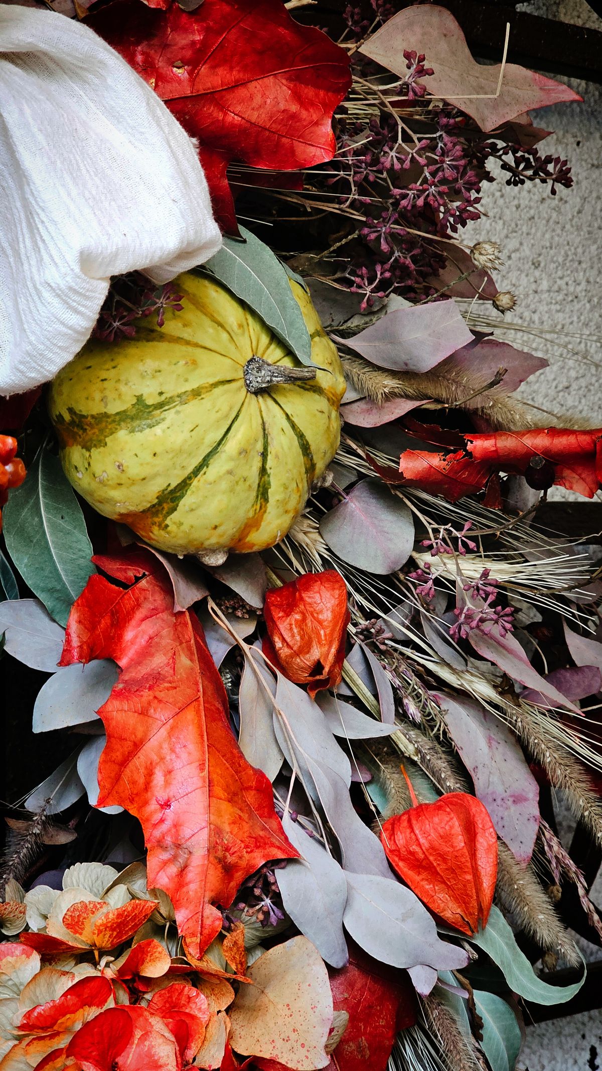 Vibrant autumn harvest wreath with mini pumpkins, leaves and dried flowers on a grapevine base