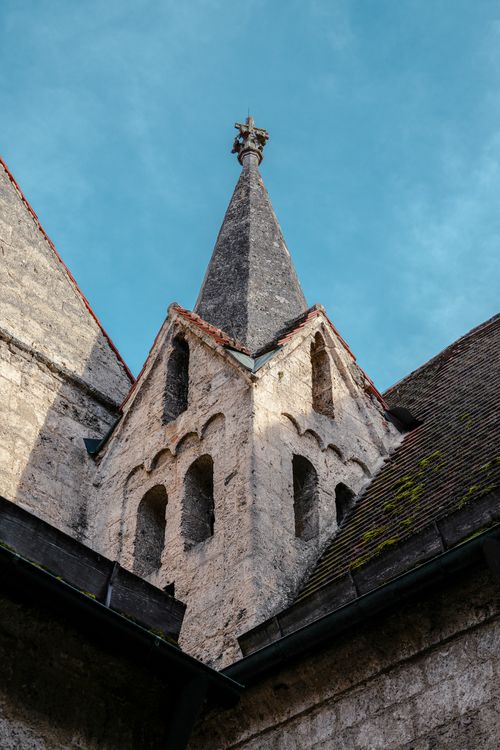 Free Stone church steeple with intricate architecture set against a clear blue sky. Stock Photo