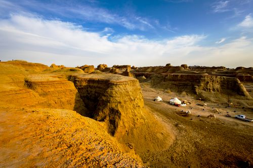 Free Breathtaking view of desert cliffs with yurts, camels, and a vibrant blue sky. Stock Photo